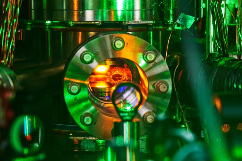 A shiny metal vacuum chamber with red light emanating from inside.