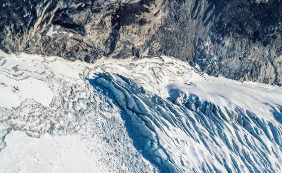 An aerial view of where bedrock, sea ice, a glacial river, crevasses, and icebergs meet. Western Greenland Ice Sheet.